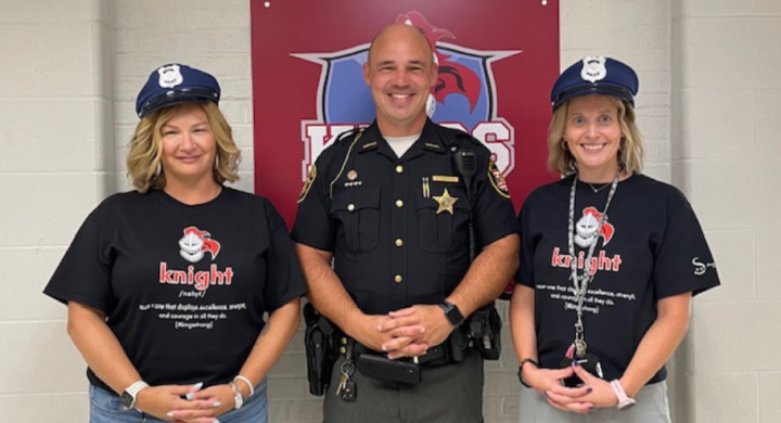 JFB secretaries Amanda and Lauren pose in police hats with school resource officer David Sheppard